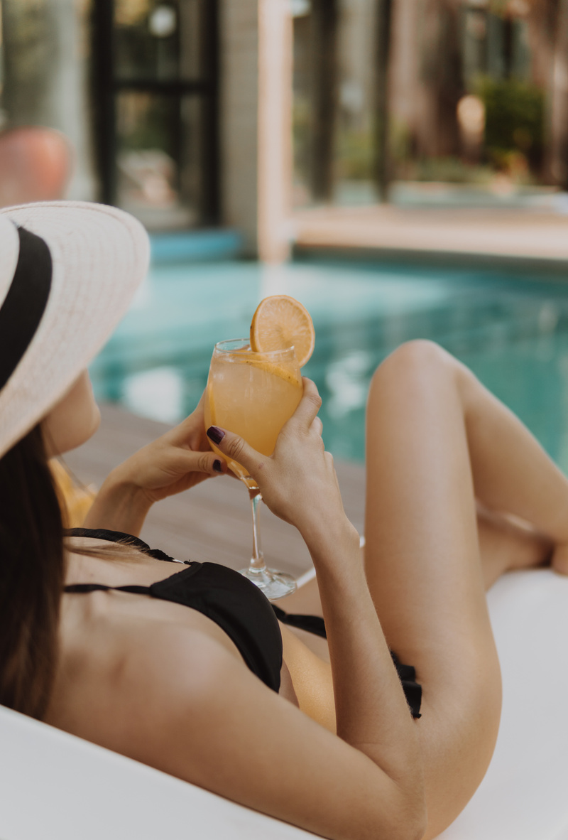 Woman in Black Bikini Holding a Glass of Orange Juice